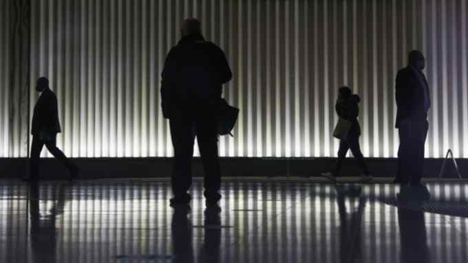Silhouettes of people walk through the lobby of an office building in the City of London