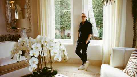 Tommy Hilfiger stands in front of the windows in his house in Palm Beach, Florida