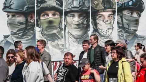 People stand near images of Russian soldiers at an exhibition in Moscow this week of weapons seized by the Russian army in Ukraine