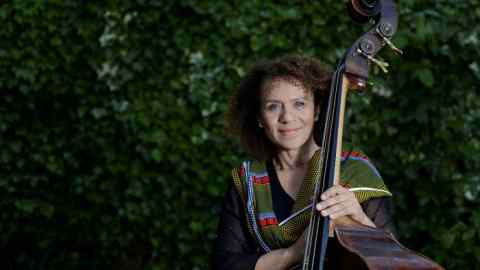 A woman in a bright scarf holds the neck of a double bass