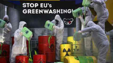 Members of KoalaKollektiv and Greenpeace pour green paint on to barrels during a protest against green washing next to the Euro Sculpture at Willi-Brandt-Platz in the financial district of Frankfurt, Germany in January 2022