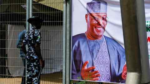 A policeman looks at the poster of Atiku Abubakar during the national convention of the People’s Democratic Party in Abuja, Nigeria, earlier this year