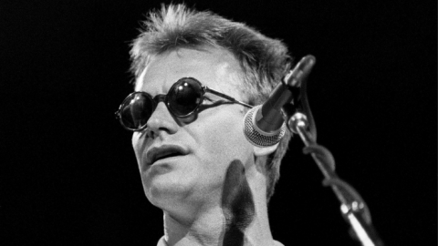 A man in sunglasses sings on stage