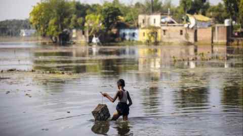 A young boy wades through flood water in India