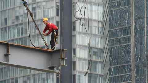 A worker stands on a beam on a construction site in Beijing