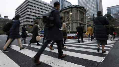 Commuters pass the Bank of Japan headquarters in Tokyo. If the BoJ tries to defend yield curve control and fails it will pay a bitter price in cash and credibility