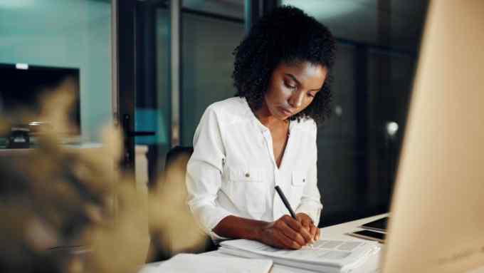 young businesswoman going through paperwork while working in an office at night