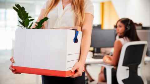 Woman holding box of belongings in an office