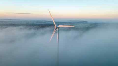 Early morning mist surrounds a wind turbine near Shepton Mallet, Somerset, UK