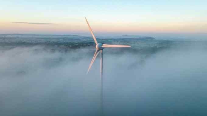 Early morning mist surrounds a wind turbine near Shepton Mallet, Somerset, UK