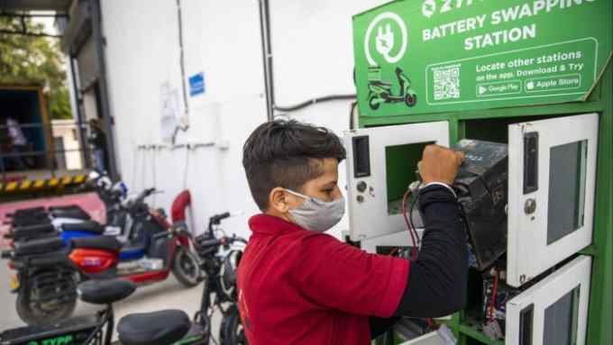 A delivery rider handles a battery at a Zypp Electric battery swapping station