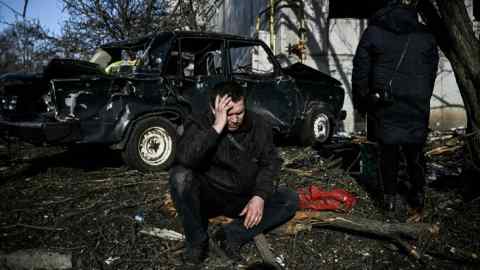 A man sits outside his destroyed building after bombings on the eastern Ukraine town of Chuguiv on Thursday