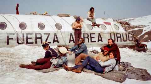Young people sitting beside a crashed plane on the snow