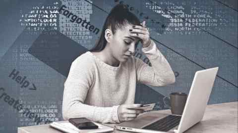Young female in front of a laptop. She is upset and looking at a credit card and touching her forehead