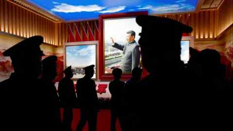 Members of the People’s Liberation Army walk past an image of Xi Jinping at an exhibition
