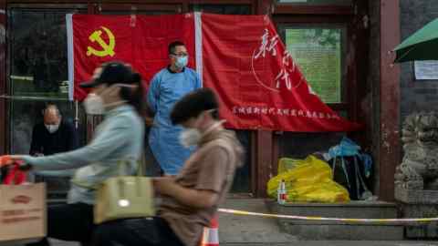 A health worker stands in front of a flag of the Chinese Communist party a at a Covid testing site in Beijing