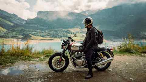Royal Enfield rider Charlie Thomas takes in a lake view in the Swiss Alps on the Great Malle Mountain Rally