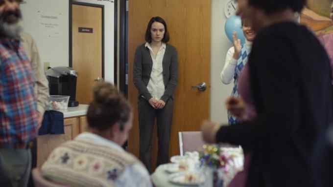 A group of office workers stares at a timid-looking young woman as she comes in the door