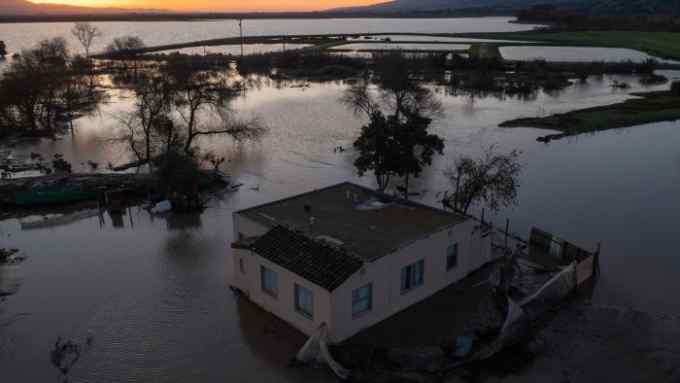 Aerial view of single-storey house at dusk surrounded by flooded fields