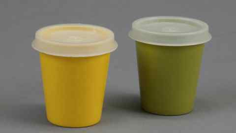 Two small Tupperware cups with snap-on lids, one yellow, one green, from the 1960s