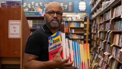Actor Jeffrey Wright holding a pile of books in a scene from the film American Fiction