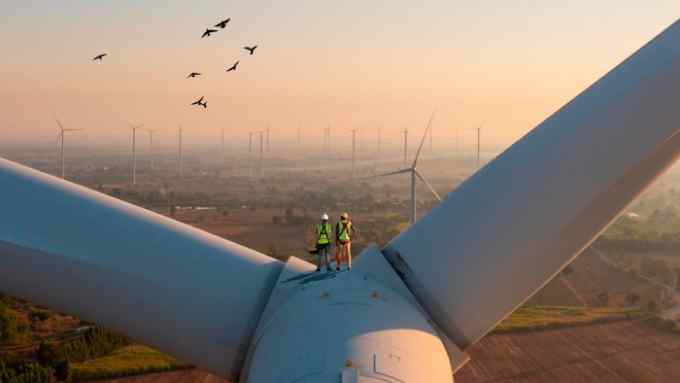Two technicians stand atop a massive wind turbine in Thailand