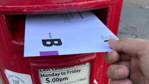 A postal vote being pushed into a letter box