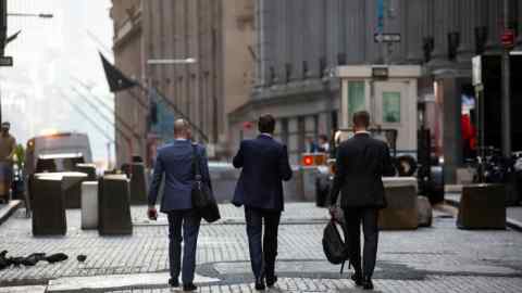 Pedestrians walk along Wall Street in New York