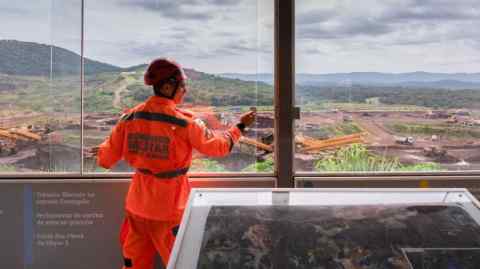 A firefighter stands at a viewpoint looking at the site where the Vale dam was located in Brumadinho