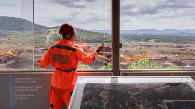 A firefighter stands at a viewpoint looking at the site where the Vale dam was located in Brumadinho