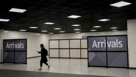 A lone airline passenger walks through the arrivals section at London’s Luton Airport