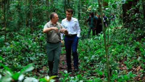 French president Emmanuel Macron walks through a rainforest area with Gabon’s environment minister Lee White