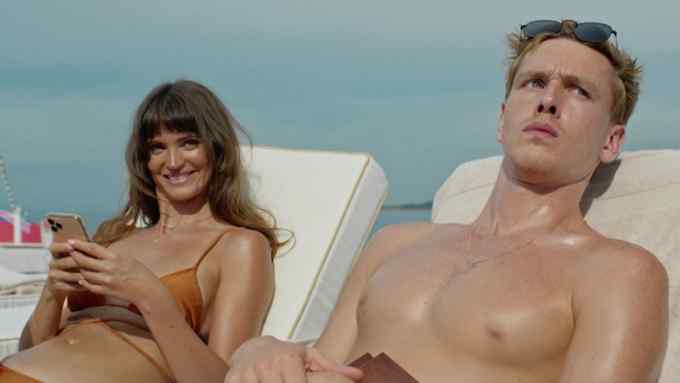Two attractive female and male models lie on sun loungers