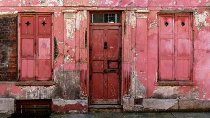 The flaking red-pink door and walls of an old building