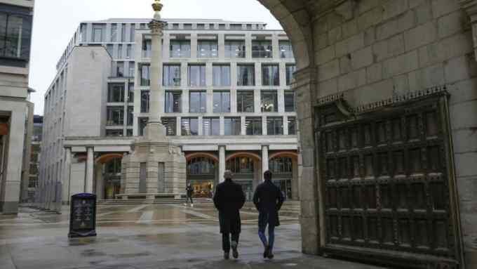 Pedestrians pass the London Stock Exchange