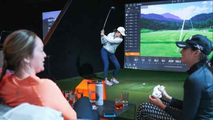 customers at a bar and restaurant that uses simulators to create a virtual driving range and a number of simulated golf courses