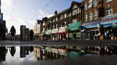Pedestrians pass shops in Barking, east London