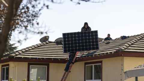 Save A Lot Solar contractors carry LG Electronics solar panels onto the roof of a home