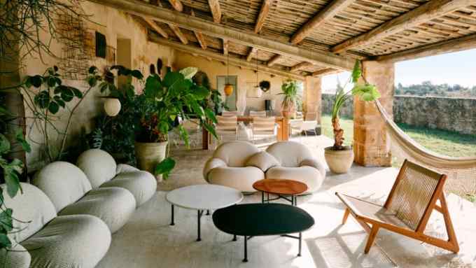 a collection of designer chairs, tables, pots and lightings placed under a wooden shed