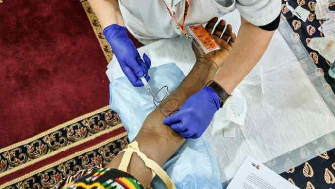 A volunteer nurse with HBV-Comsava takes a blood sample in a mosque