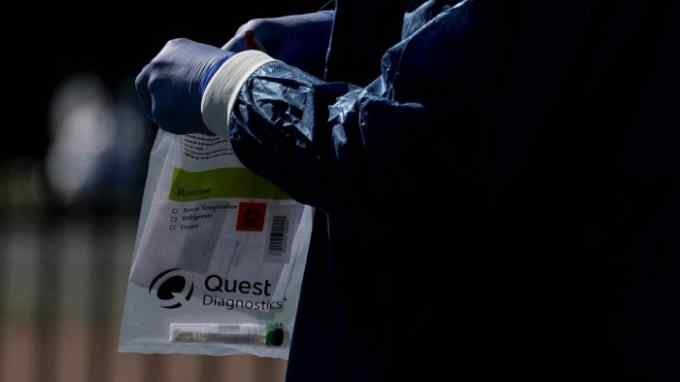 A healthcare worker holds a Quest Diagnostics bag containing a Covid-19 swab at a coronavirus drive-through testing site in Washington DC
