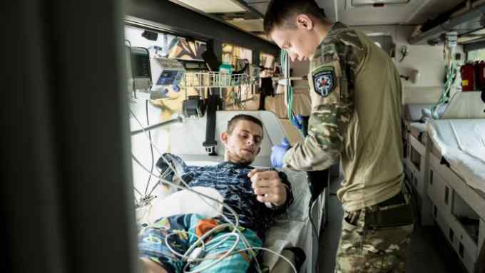 A paramedic measures the blood pressure of a wounded soldier at a mobile clinic