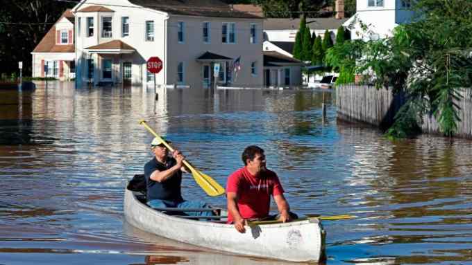 Two men on a kayak in a flooded neighbourhood
