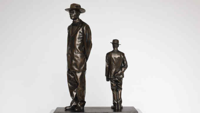 bronze statue of two men standing in hats, one far taller than the other