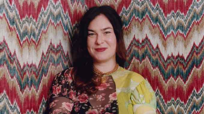 Rachel Chudley wearing a floral and yellow dress in front of a patterned wall