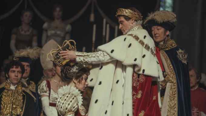 A man in regal attire crowns a woman also in regal attire