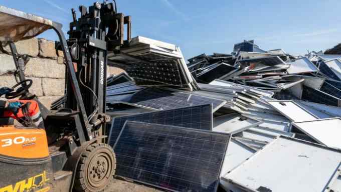 A fork lift truck faces a heap of used solar panels at a facility run by Soren