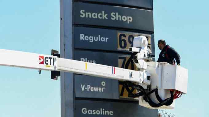 An electrical contractor uses a hydraulic platform to reach a price display at a Los Angeles petrol station